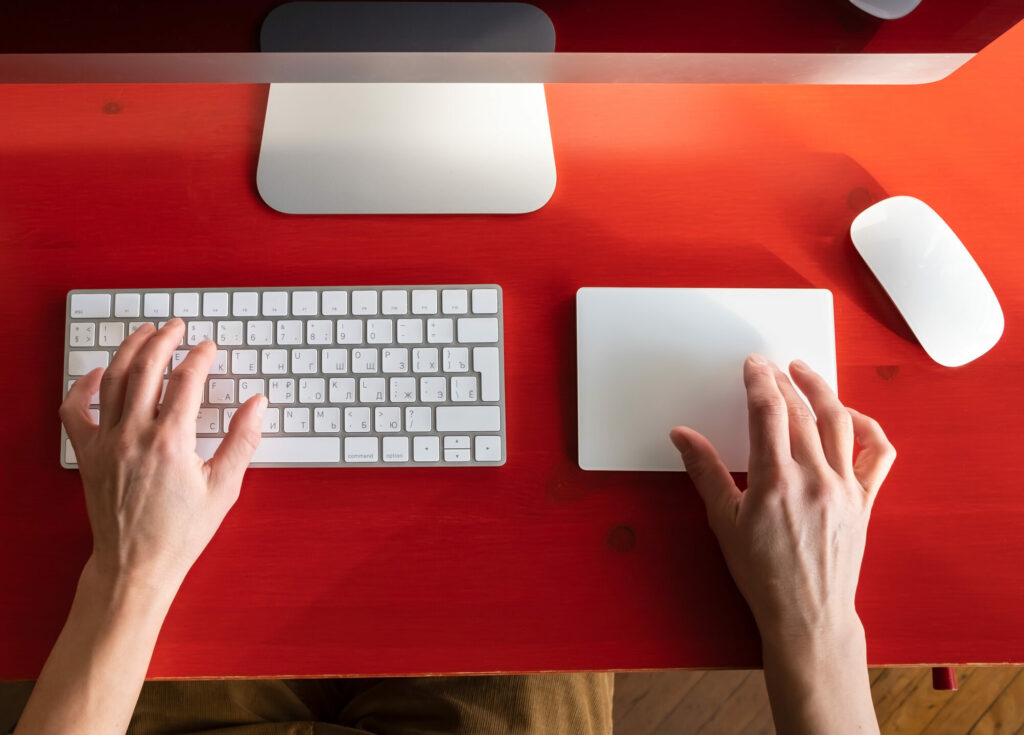 Female hands work with a keyboard and a touchpad, a mouse and a computer are nearby. Remote work. Contemporary workplace.